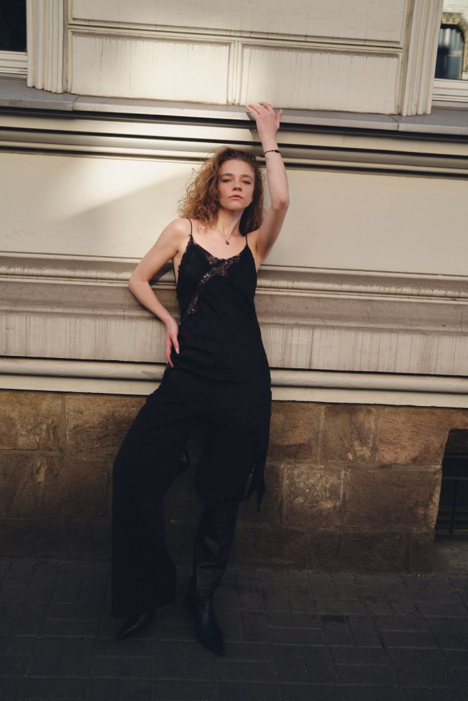 Fotografia mody w plenerze miejskim, modelka w czarnym topie i szerokich spodniach